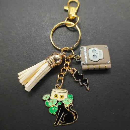 Porte-clé Chat Noir Ghost sur fond noir, contraste élégant mettant en valeur les finitions dorées