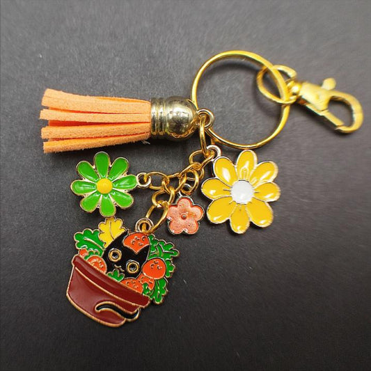 Porte-clé chat noir dans un pot de champignons colorés, pompon orange