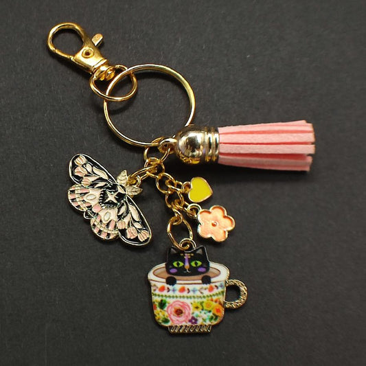Porte-clé chat tricolore dans tasse fleurie russe avec papillon noir