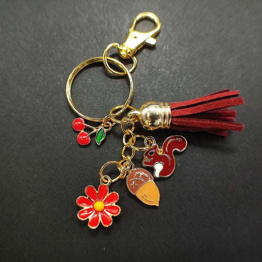 Porte-clé avec écureuil marron foncé-rouge, cerises rouges, fleurs rouges et pompon rouge.
