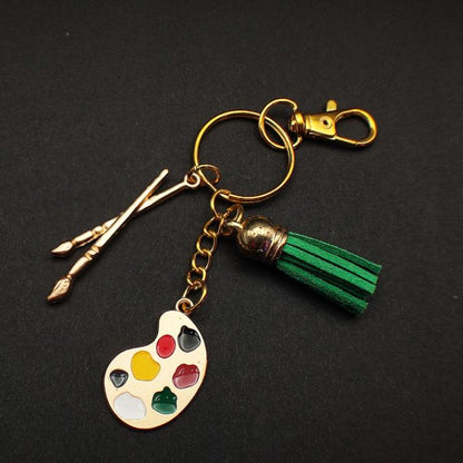 Porte clé Original en métal émaillé avec pompon en cuir, représentant une palette de peintre et des pinceaux