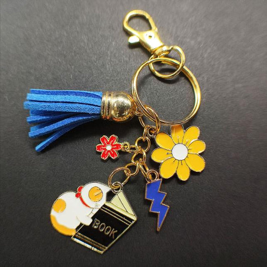 Fiche produit porte clé Chat blanc et jaune kawaii avec un livre noir et des fleurs 