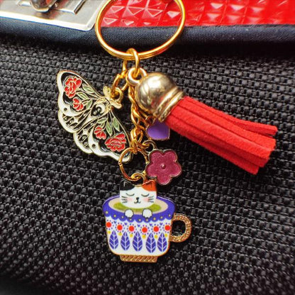 Porte-clé chat tricolore dans tasse fleurie russe avec papillon noir